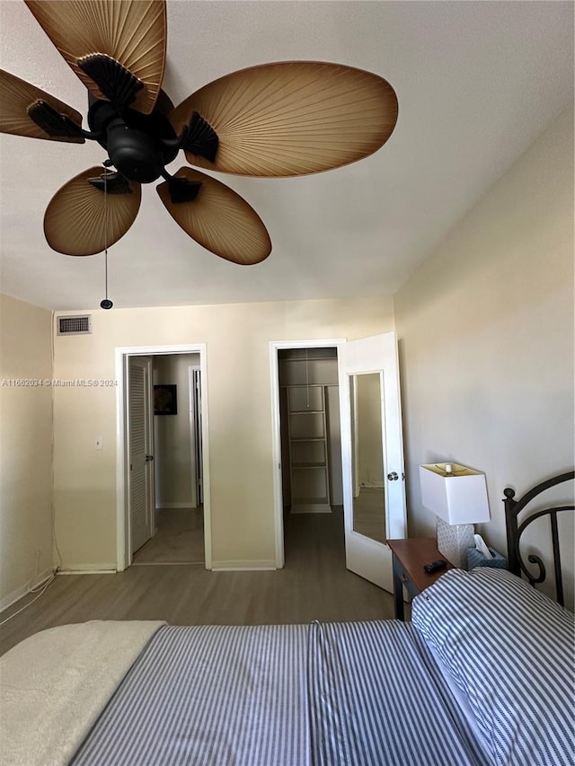 unfurnished bedroom featuring ceiling fan, a closet, dark hardwood / wood-style floors, and a walk in closet