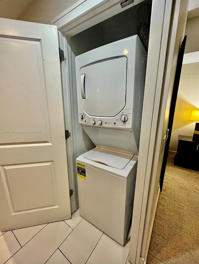 laundry area featuring stacked washer / dryer and light tile patterned floors