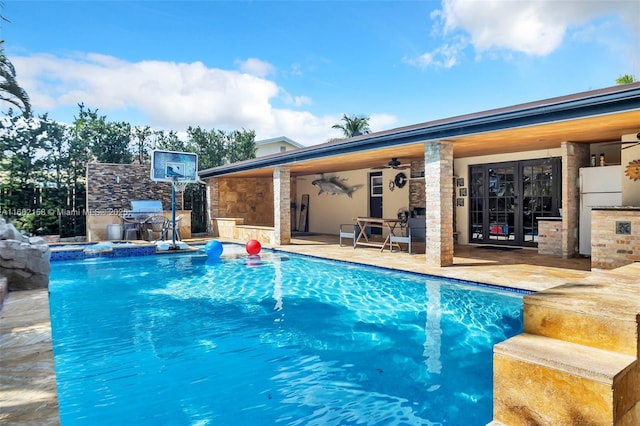 view of pool with ceiling fan, exterior kitchen, and a patio