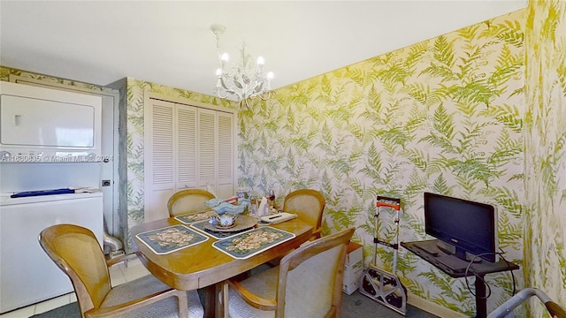 tiled dining room with a chandelier and stacked washer and dryer