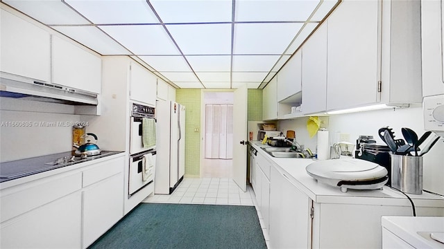 kitchen with white cabinets, light tile patterned floors, sink, white appliances, and washer / dryer