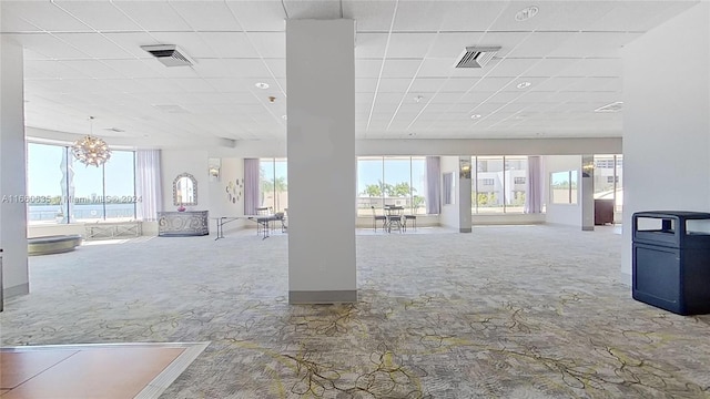 interior space with an inviting chandelier, a paneled ceiling, and plenty of natural light