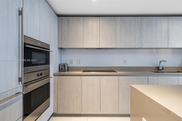 kitchen featuring black electric cooktop, sink, range hood, and stainless steel oven