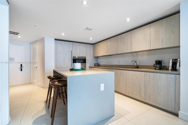 kitchen with oven, a kitchen bar, light tile patterned flooring, modern cabinets, and a sink