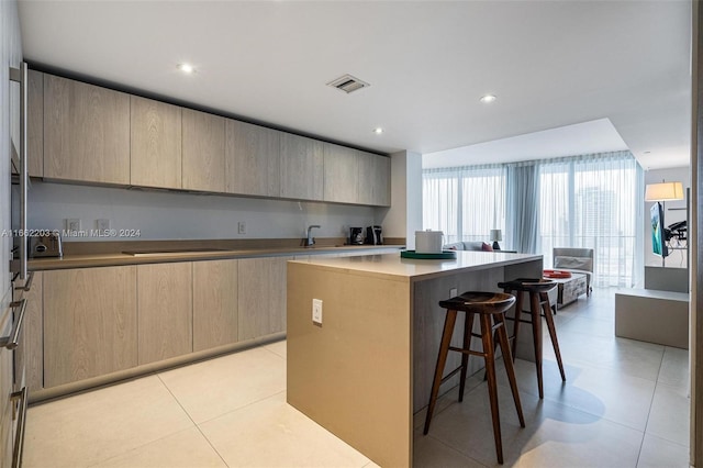 kitchen featuring visible vents, a breakfast bar, light brown cabinetry, modern cabinets, and a center island