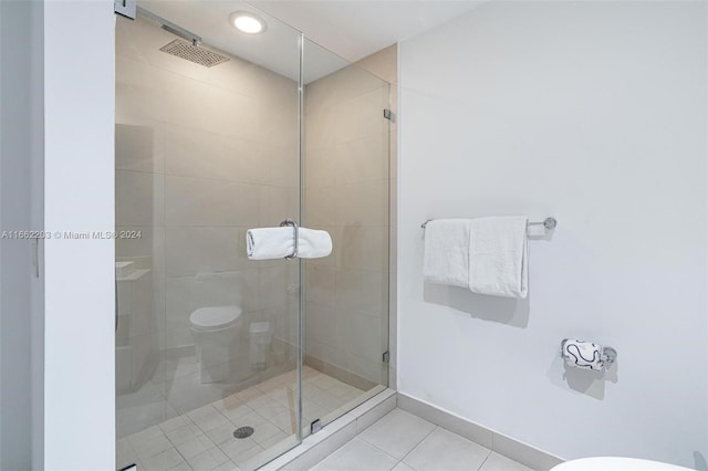 bathroom with tile patterned floors, a shower with shower door, and toilet