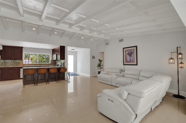 tiled living room featuring lofted ceiling with beams and track lighting