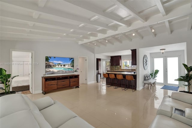 tiled living room with lofted ceiling with beams, track lighting, and french doors