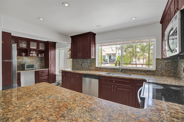 kitchen featuring backsplash, sink, stainless steel appliances, and light stone countertops