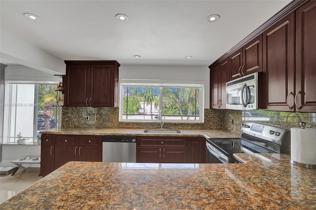 kitchen with light stone counters, appliances with stainless steel finishes, tasteful backsplash, and sink