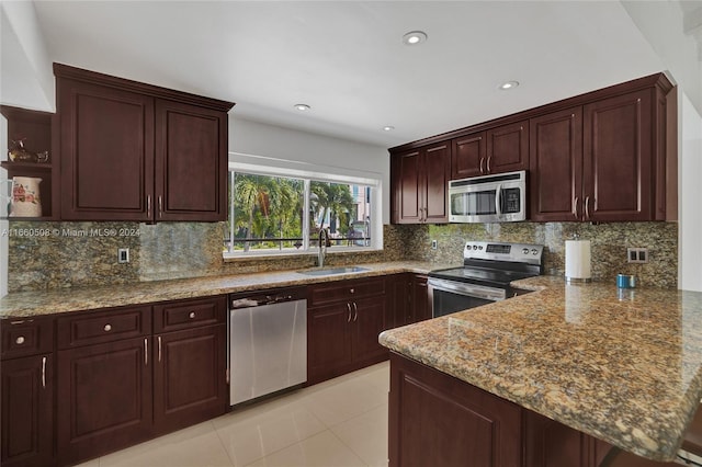 kitchen with appliances with stainless steel finishes, decorative backsplash, sink, and light stone counters