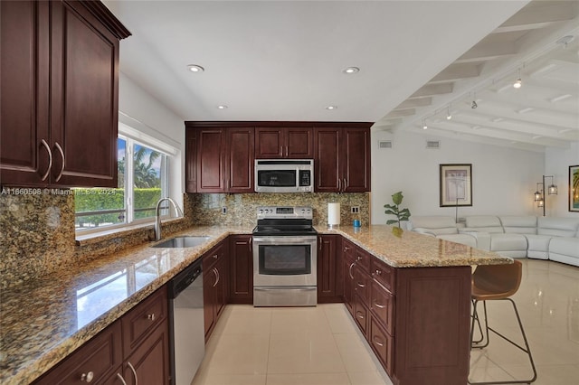 kitchen with lofted ceiling with beams, tasteful backsplash, sink, a kitchen breakfast bar, and appliances with stainless steel finishes