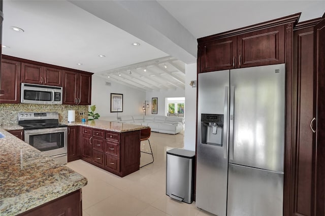 kitchen featuring appliances with stainless steel finishes, backsplash, kitchen peninsula, light stone countertops, and vaulted ceiling with beams