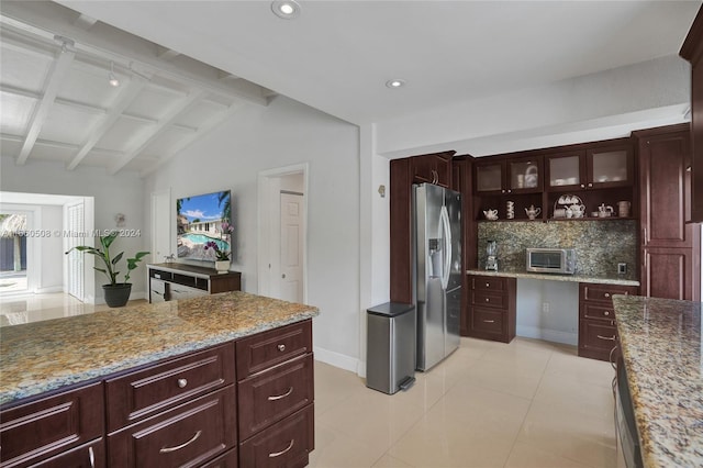 kitchen featuring stainless steel fridge, lofted ceiling with beams, tasteful backsplash, light stone countertops, and light tile patterned floors