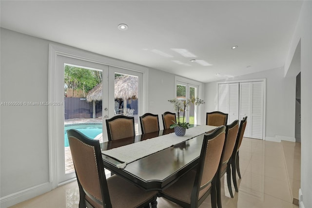 tiled dining space featuring vaulted ceiling and french doors