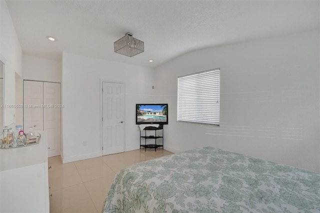 tiled bedroom featuring vaulted ceiling and a textured ceiling