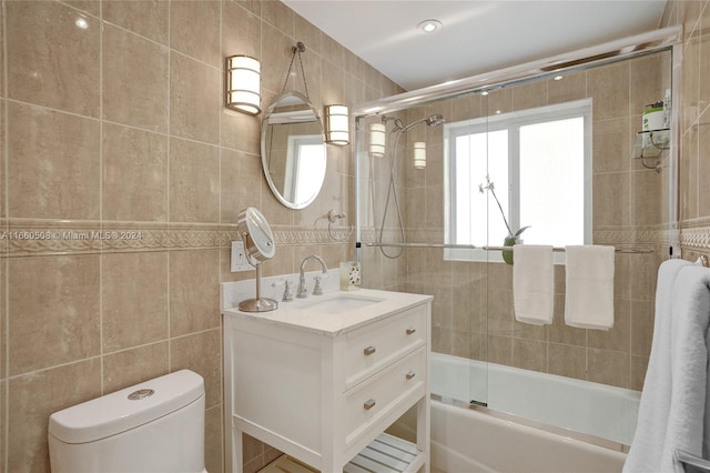 full bathroom with tile walls, vanity, enclosed tub / shower combo, and toilet