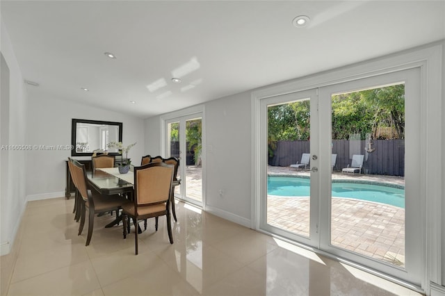 dining space featuring lofted ceiling, light tile patterned floors, and french doors