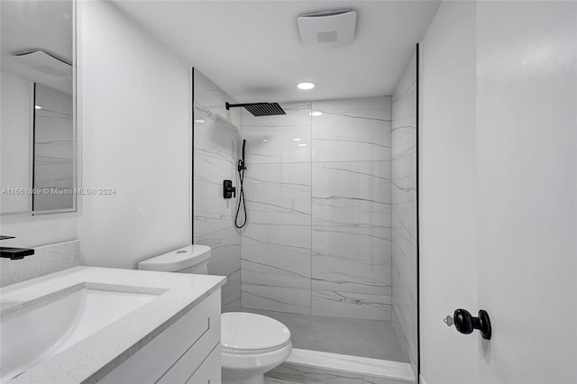 bathroom featuring a tile shower, vanity, and toilet