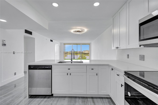 kitchen featuring white cabinets, kitchen peninsula, appliances with stainless steel finishes, and sink