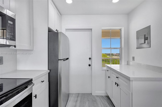 kitchen featuring light wood-type flooring, white cabinetry, appliances with stainless steel finishes, and electric panel