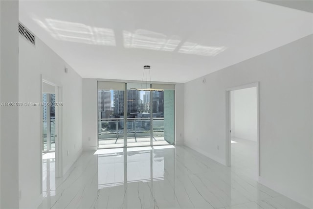 empty room featuring baseboards, visible vents, marble finish floor, and expansive windows