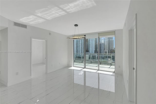 empty room featuring floor to ceiling windows, baseboards, visible vents, and marble finish floor