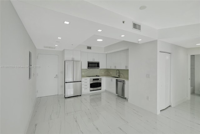 kitchen featuring marble finish floor, a sink, white cabinetry, appliances with stainless steel finishes, and light countertops