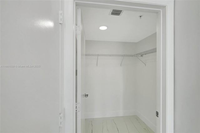 spacious closet featuring visible vents and marble finish floor