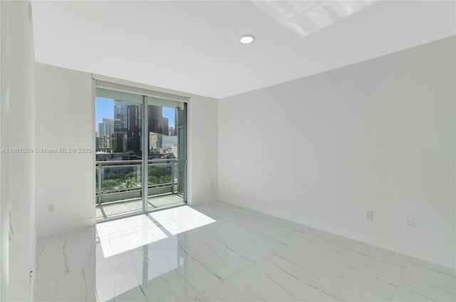 unfurnished room with a wall of windows, a view of city, baseboards, and marble finish floor