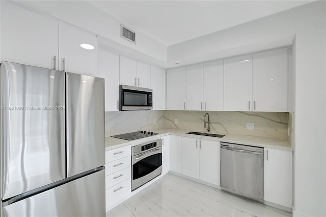 kitchen with marble finish floor, white cabinetry, stainless steel appliances, and a sink