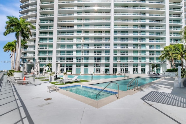 pool with a patio area and a community hot tub