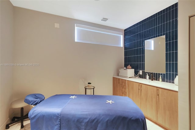 bedroom featuring tile walls, visible vents, and a sink