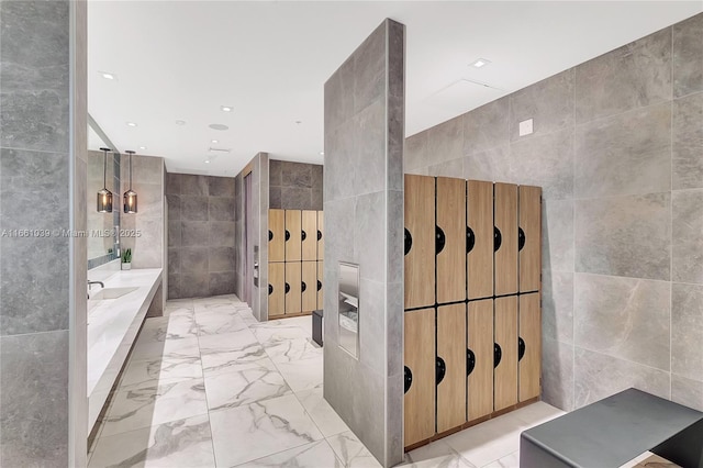 bathroom with recessed lighting, marble finish floor, tile walls, and a bath