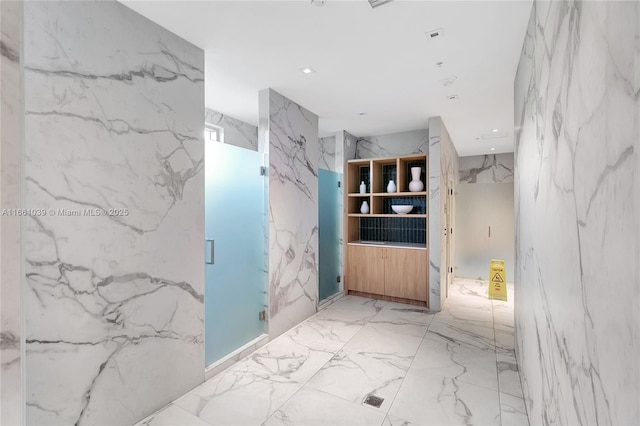 full bathroom featuring recessed lighting, a marble finish shower, marble finish floor, and stone wall