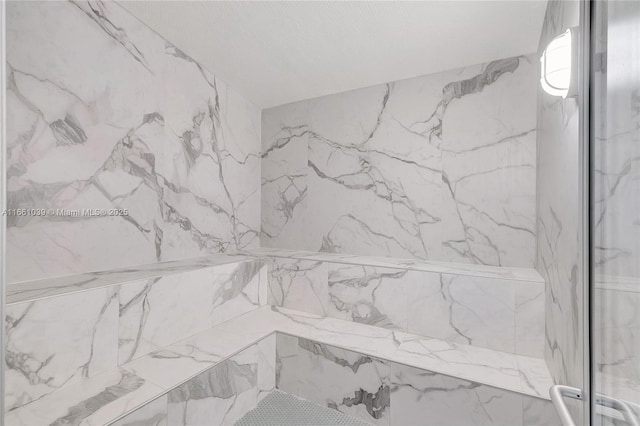 interior details with a marble finish shower and a textured ceiling