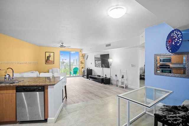 kitchen featuring ceiling fan, sink, kitchen peninsula, a breakfast bar area, and appliances with stainless steel finishes