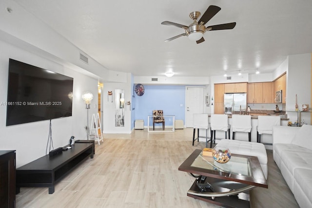 living room featuring light hardwood / wood-style flooring and ceiling fan