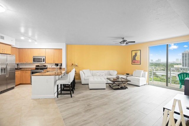 living room with ceiling fan, sink, and a textured ceiling