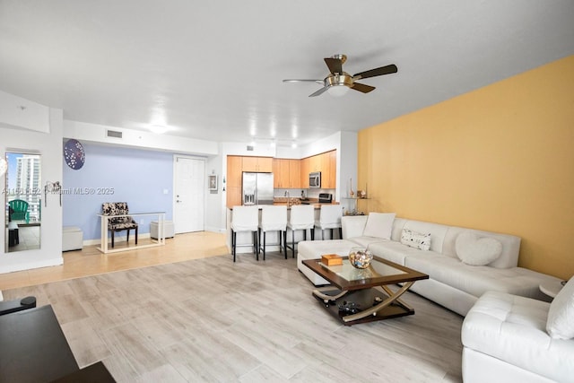 living room featuring ceiling fan and light hardwood / wood-style floors