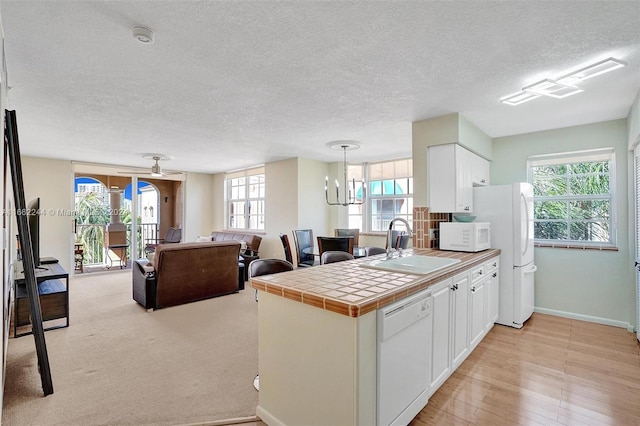 kitchen featuring tile countertops, white appliances, and a wealth of natural light