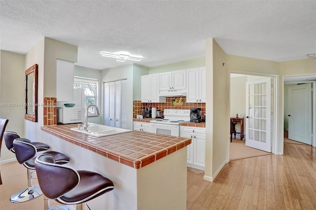 kitchen featuring light hardwood / wood-style floors, sink, white cabinetry, white appliances, and tile countertops