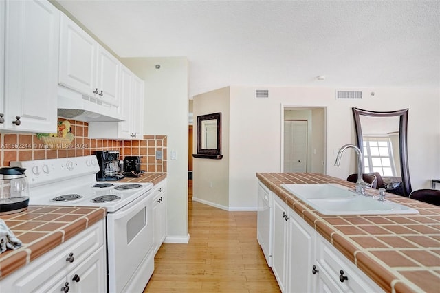 kitchen with light hardwood / wood-style floors, white cabinets, white appliances, tile counters, and sink