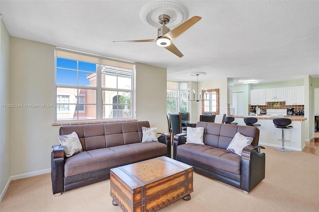 carpeted living room with ceiling fan with notable chandelier and a textured ceiling