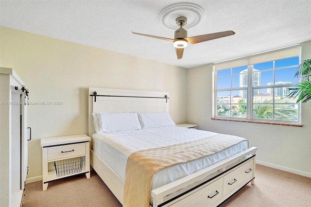 bedroom featuring light carpet, ceiling fan, and a textured ceiling