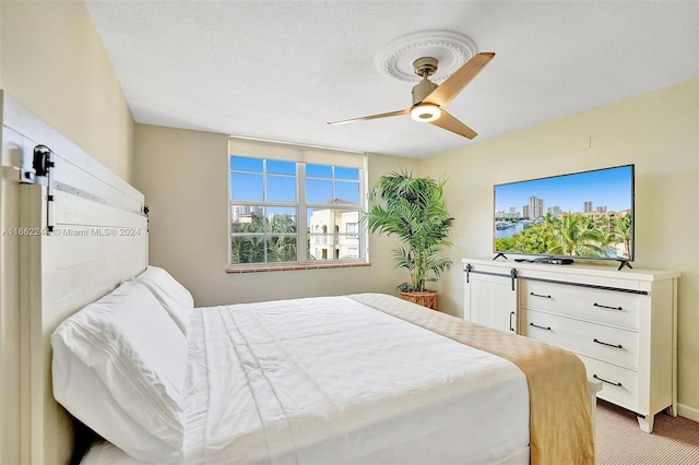 carpeted bedroom featuring a barn door, a textured ceiling, and ceiling fan