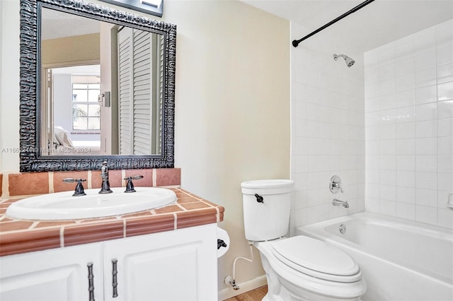 full bathroom with tiled shower / bath, vanity, and toilet