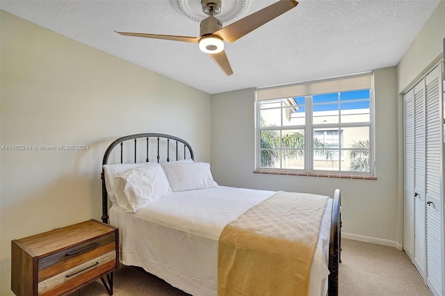 bedroom with a closet, ceiling fan, carpet floors, and a textured ceiling