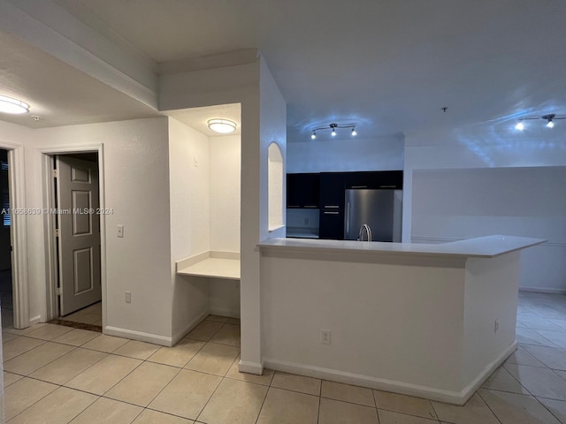 kitchen with light tile patterned floors, stainless steel fridge, and kitchen peninsula