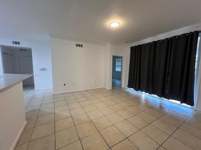 empty room with a textured ceiling and light tile patterned floors